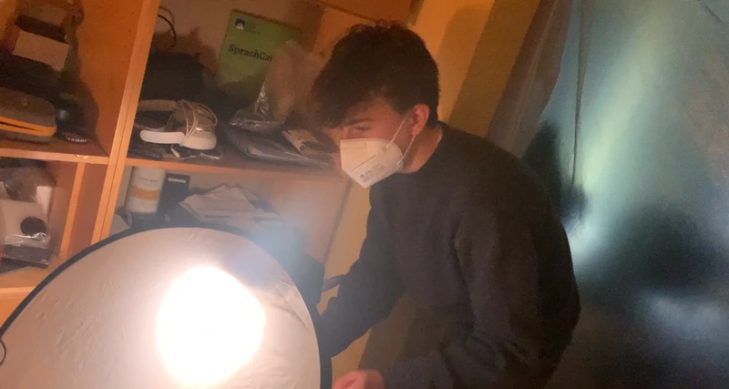 Luis mit Maske richtet eine Lampe und einen Reflektor ein