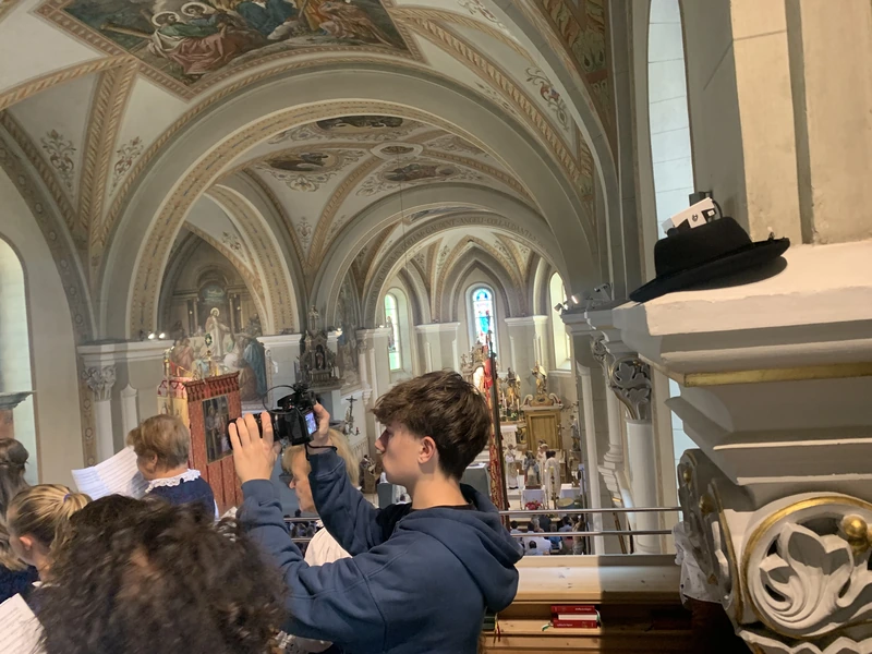Luis filmt von der Empore aus den Festgottesdienst in einer bemalten Dorfkirche
