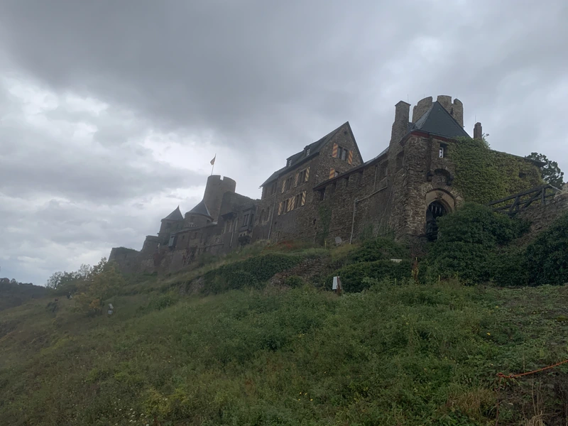 Eine Burg auf einem grünen Hügel unter grauem Himmel